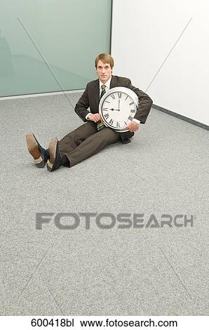 businessman sitting in corner holding clock View Large Photo Image Stock Image - businessman sitting in corner holding clock. Fotosearch