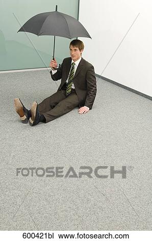businessman sitting in corner holding umbrella View Large Photo Image Stock Image - businessman sitting in corner holding umbrella. Fotosearch