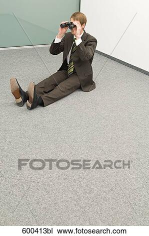 Stock Image - businessman sitting in corner looking through binoculars. Fotosearch