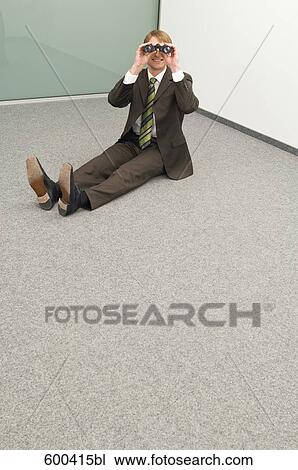 Stock Image - businessman sitting in corner looking through binoculars. Fotosearch