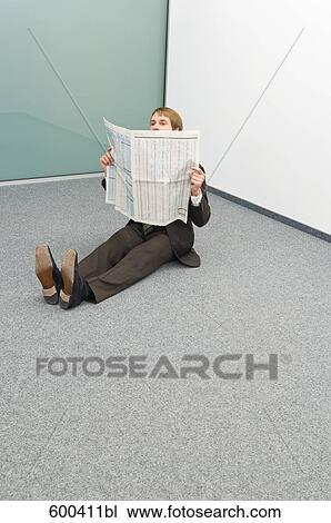 Stock Image - businessman sitting in corner reading newspaper. Fotosearch