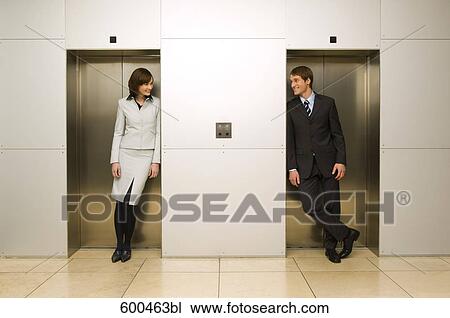 businesswoman and male colleague standing in elevator doors flirting with each other View Large Photo Image Stock Image - businesswoman and male colleague standing in elevator doors flirting with each other. Fotosearch