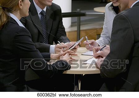 close-up of four business people sitting around conference table View Large Photo Image Stock Image - close-up of four business people sitting around conference table. Fotosearch