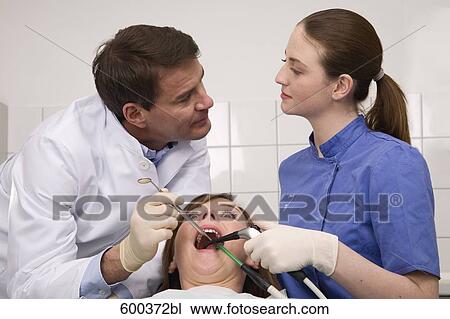 Stock Image - dentist and assistant flirting with each other while examining patient. Fotosearch