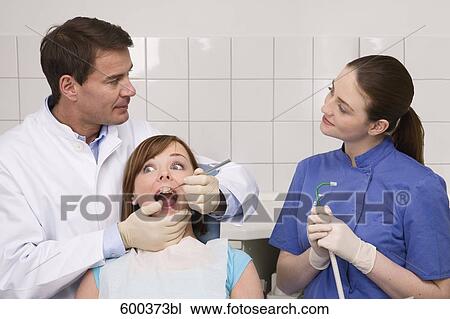 Stock Image - dentist and assistant flirting with each other while examining patient. Fotosearch