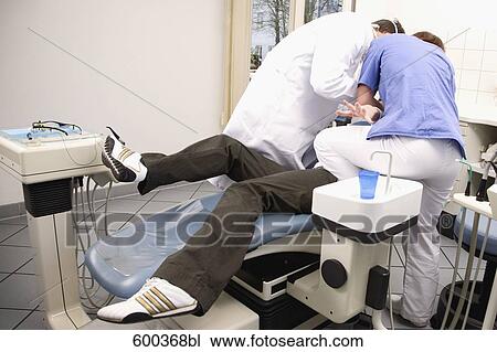 dentist and assistant trying to examine fearful patient View Large Photo Image Stock Image - dentist and assistant trying to examine fearful patient. Fotosearch
