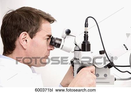 Stock Image - dentist looking through medical instrument. Fotosearch