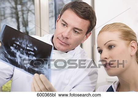 Stock Image - dentist showing female patient x-ray of her teeth . Fotosearch