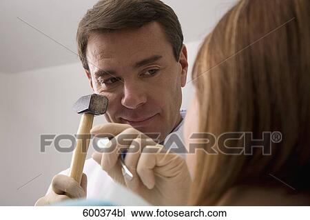 Stock Image - dentist treating female patient with hammer and chisel. Fotosearch