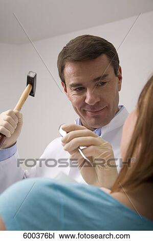 Stock Image - dentist treating female patient with hammer and chisel. Fotosearch