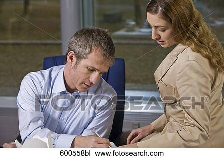 Stock Image - exhausted businessman signing document for secretary. Fotosearch