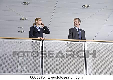 Stock Image - female executive looking at male colleague leaving for business travel. Fotosearch
