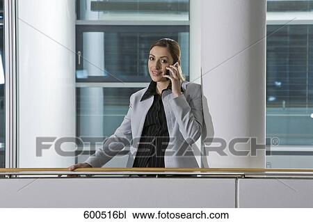 female executive talking on mobile phone in corridor of offfice building View Large Photo Image Stock Image - female executive talking on mobile phone in corridor of offfice building. Fotosearch