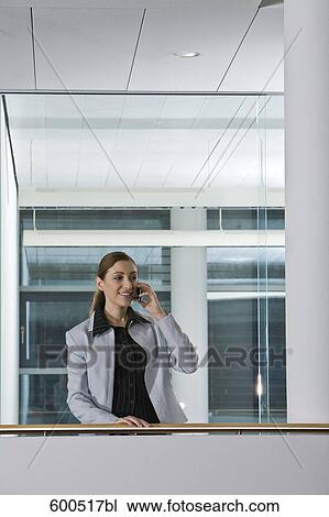 female executive talking on mobile phone in corridor of offfice building View Large Photo Image Stock Image - female executive talking on mobile phone in corridor of offfice building. Fotosearch