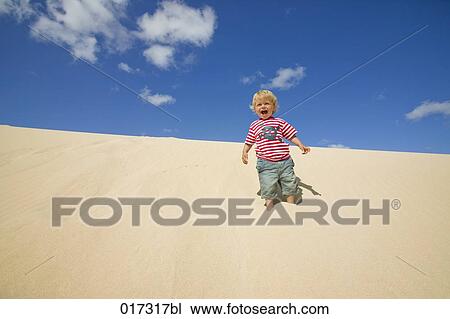 happy little boy standing on sand dune View Large Photo Image Stock Image - happy little boy standing on sand dune. Fotosearch