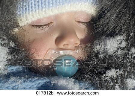 Stock Image - headshot of baby in winter clothes sleep with pacifier. Fotosearch