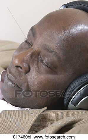 Stock Image - headshot of black businessman with earphones listening to music . Fotosearch