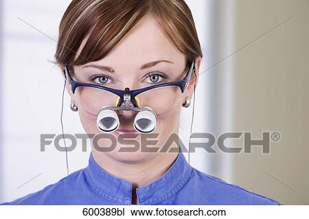 Stock Image - headshot of medical assistant wearing special magnifying glasses. Fotosearch