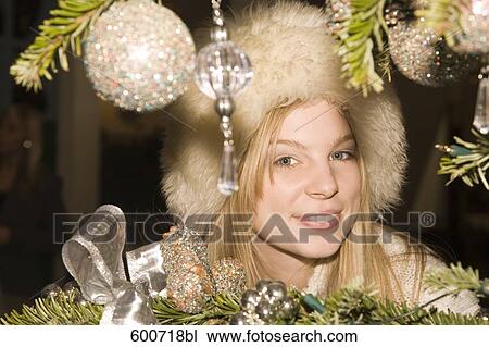 headshot of young woman peeking behind christmas tree View Large Photo Image Stock Image - headshot of young woman peeking behind christmas tree . Fotosearch