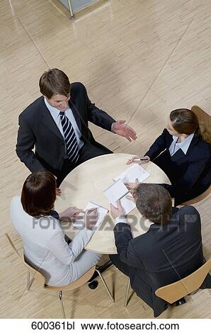 Stock Image - high angle view of four business people sitting around conference table. Fotosearch