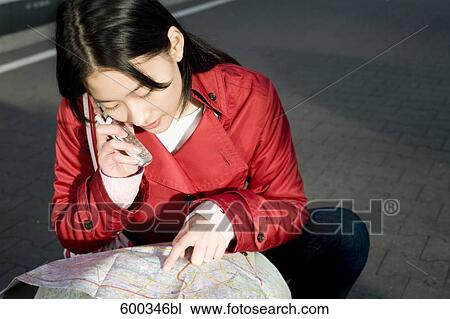 japanese woman sitting on platform of station looking at map and talking on mobile phone View Large Photo Image Stock Image - japanese woman sitting on platform of station looking at map and talking on mobile phone. Fotosearch