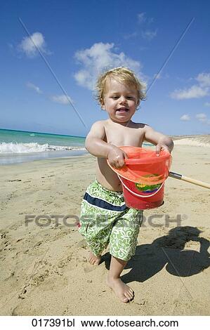 little boy walking on beach holding bucket View Large Photo Image Stock Image - little boy walking on beach holding bucket. Fotosearch