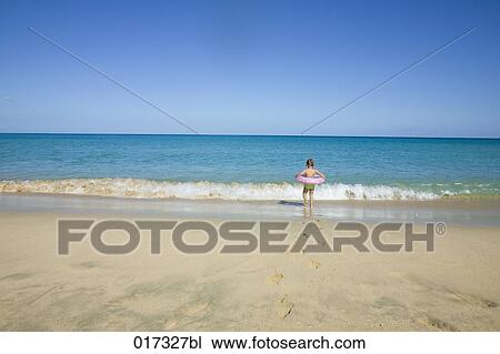 little girl with floating tyre walking into ocean surf View Large Photo Image Stock Image - little girl with floating tyre walking into ocean surf. Fotosearch