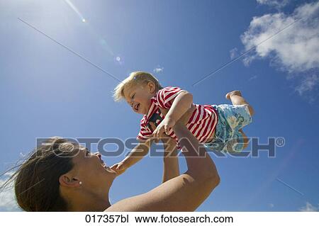 mother holding her young son up in the air View Large Photo Image Stock Image - mother holding her young son up in the air. Fotosearch