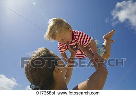 Stock Image - mother holding her young son up in the air. Fotosearch