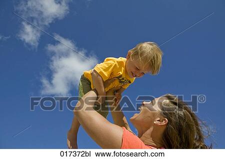 mother holding her young son up in the air View Large Photo Image Stock Image - mother holding her young son up in the air. Fotosearch
