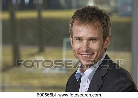 Stock Image - portrait of businessman in front of window. Fotosearch