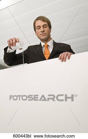 Stock Image - portrait of businessman pouring water from paper cup. Fotosearch