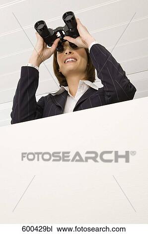 Stock Image - portrait of businesswoman looking through binoculars. Fotosearch