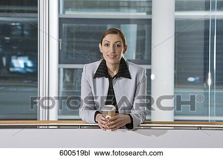 Stock Image - portrait of female executive having coffee break in corridor of office building. Fotosearch