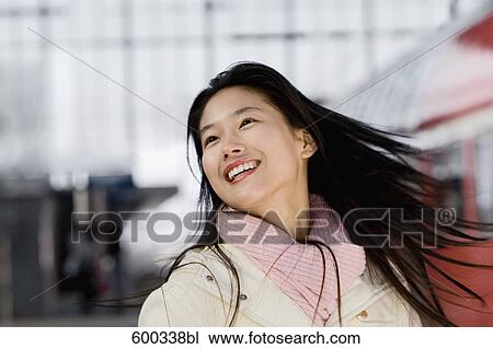 Stock Image - portrait of smiling japanese woman at train station. Fotosearch