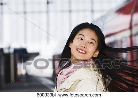 Stock Image - portrait of smiling japanese woman at train station. Fotosearch