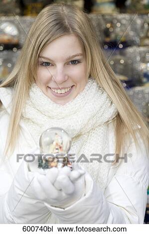 Stock Image - portrait of young woman holding snow globe. Fotosearch