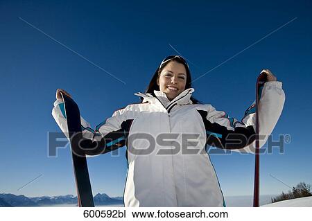 Stock Image - portrait of young woman in the mountains with skis. Fotosearch