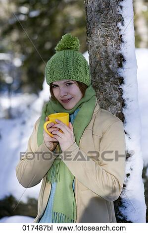 Stock Image - portrait of young woman in winter drinking hot tea. Fotosearch