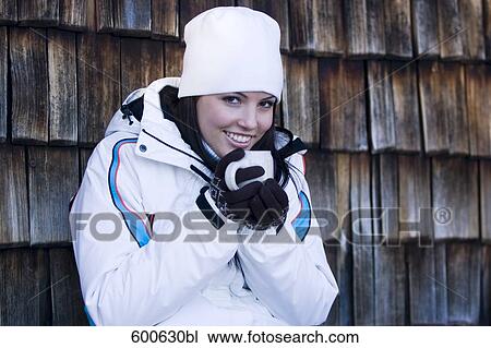 Stock Image - portrait of young woman in winter clothes having hot drink. Fotosearch