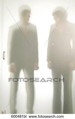 Shapes Of Businessman And Female Colleague Behind Glass Door Stock