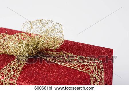 Stock Image - still life of red present with golden ribbon. Fotosearch