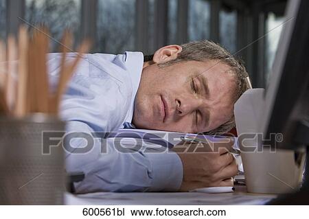 Stock Image - tired businessman asleep at his desk. Fotosearch