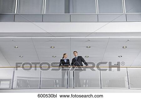 Stock Image - two executives having conversation in office building. Fotosearch