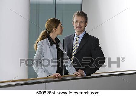 two executives standing at railing in office building View Large Photo Image Stock Image - two executives standing at railing in office building. Fotosearch