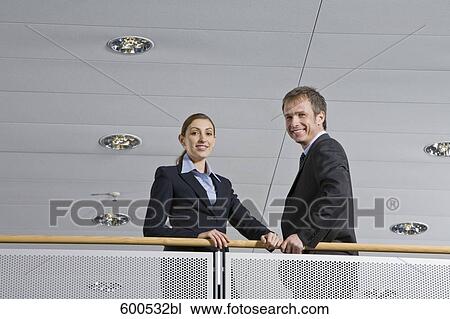 two executives standing at railing in office building View Large Photo Image Stock Image - two executives standing at railing in office building. Fotosearch