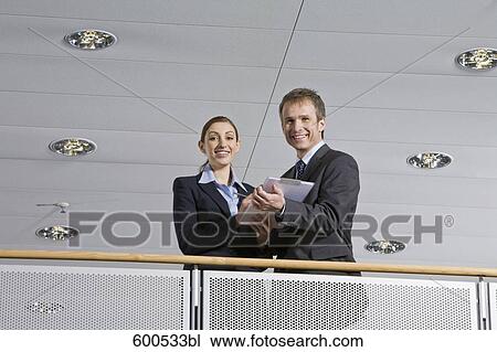 two executives standing at railing in office building View Large Photo Image Stock Image - two executives standing at railing in office building. Fotosearch