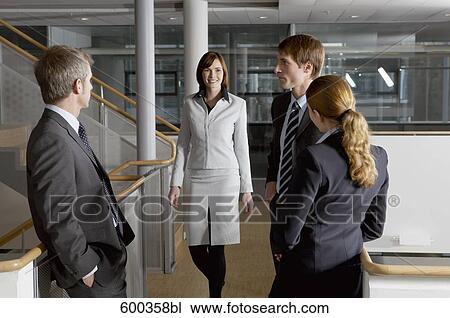 Stock Image - young businesswoman joining group of three colleagues. Fotosearch