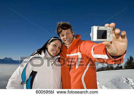 Stock Image - young couple in the mountains taking photo of themselves. Fotosearch