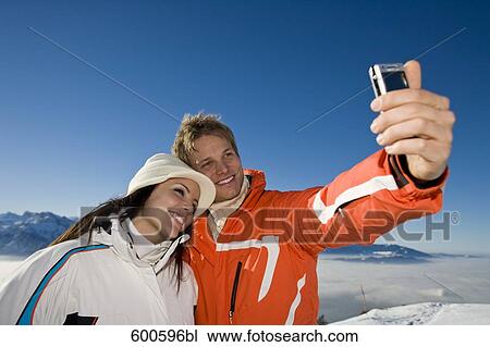young couple in the mountains taking photo of themselves View Large Photo Image Stock Image - young couple in the mountains taking photo of themselves. Fotosearch